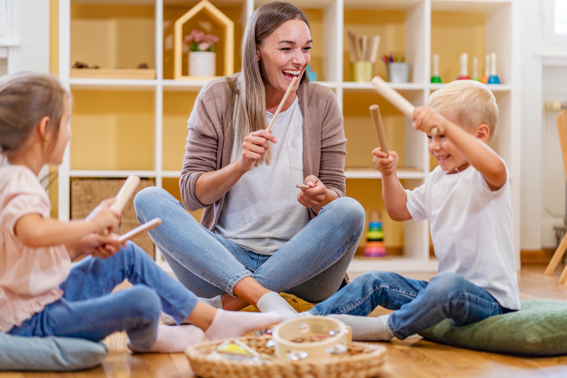 Kindergarten teacher with children sitting on the floor having music class, using various instruments and percussion
